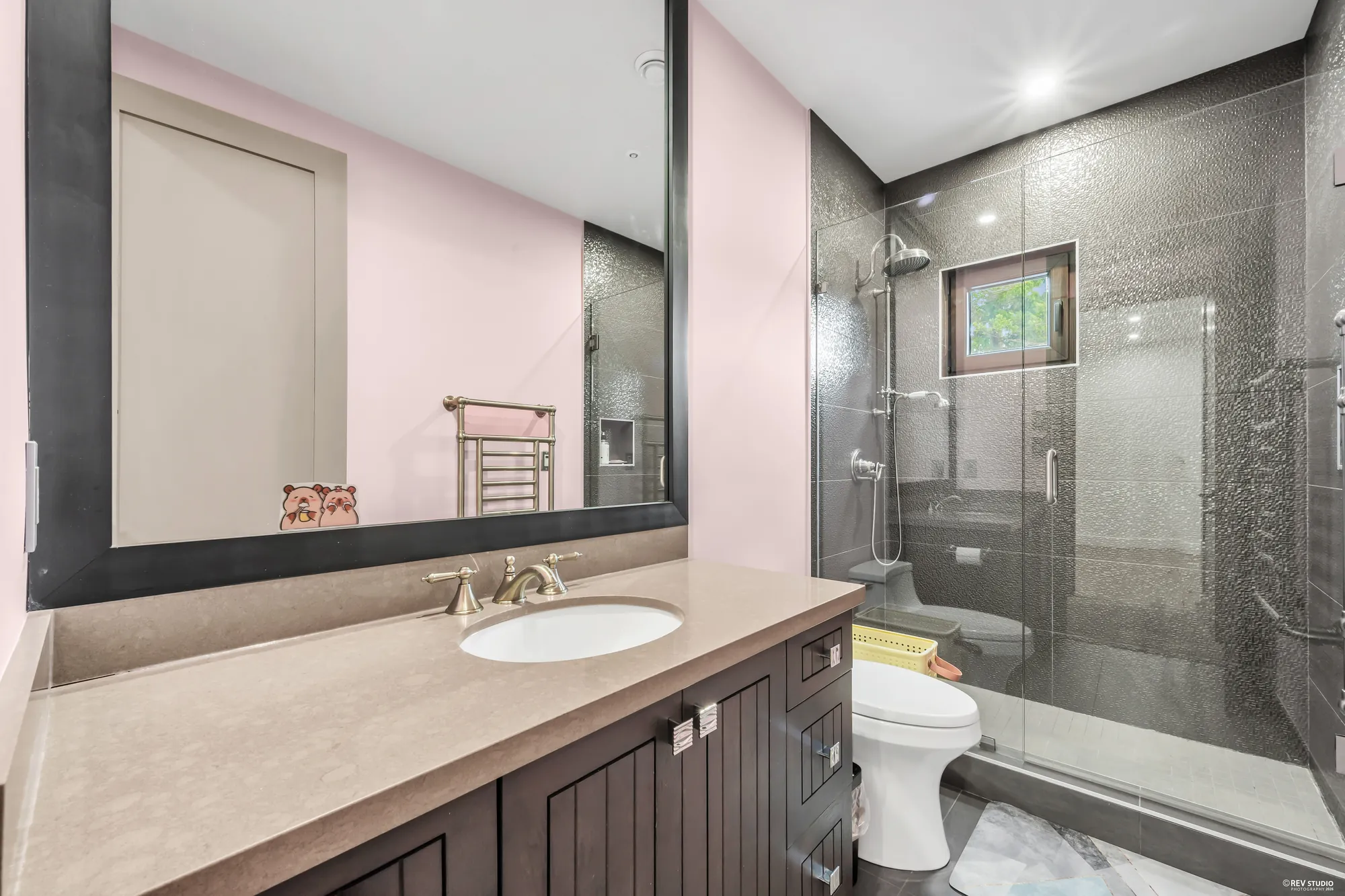 That bedroom's bathroom: a glass shower in dark tile, a vanity with a stone top