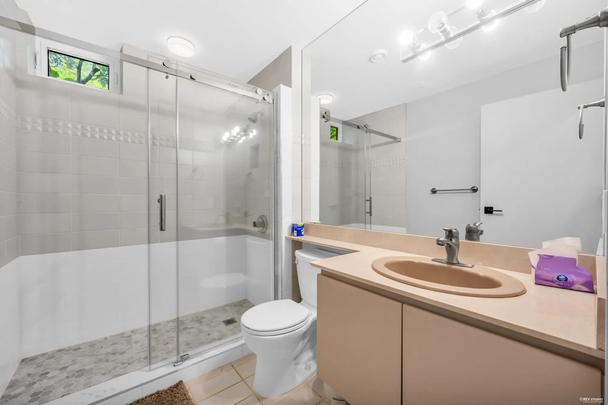 A lower bathroom with a glass shower and a vanity
