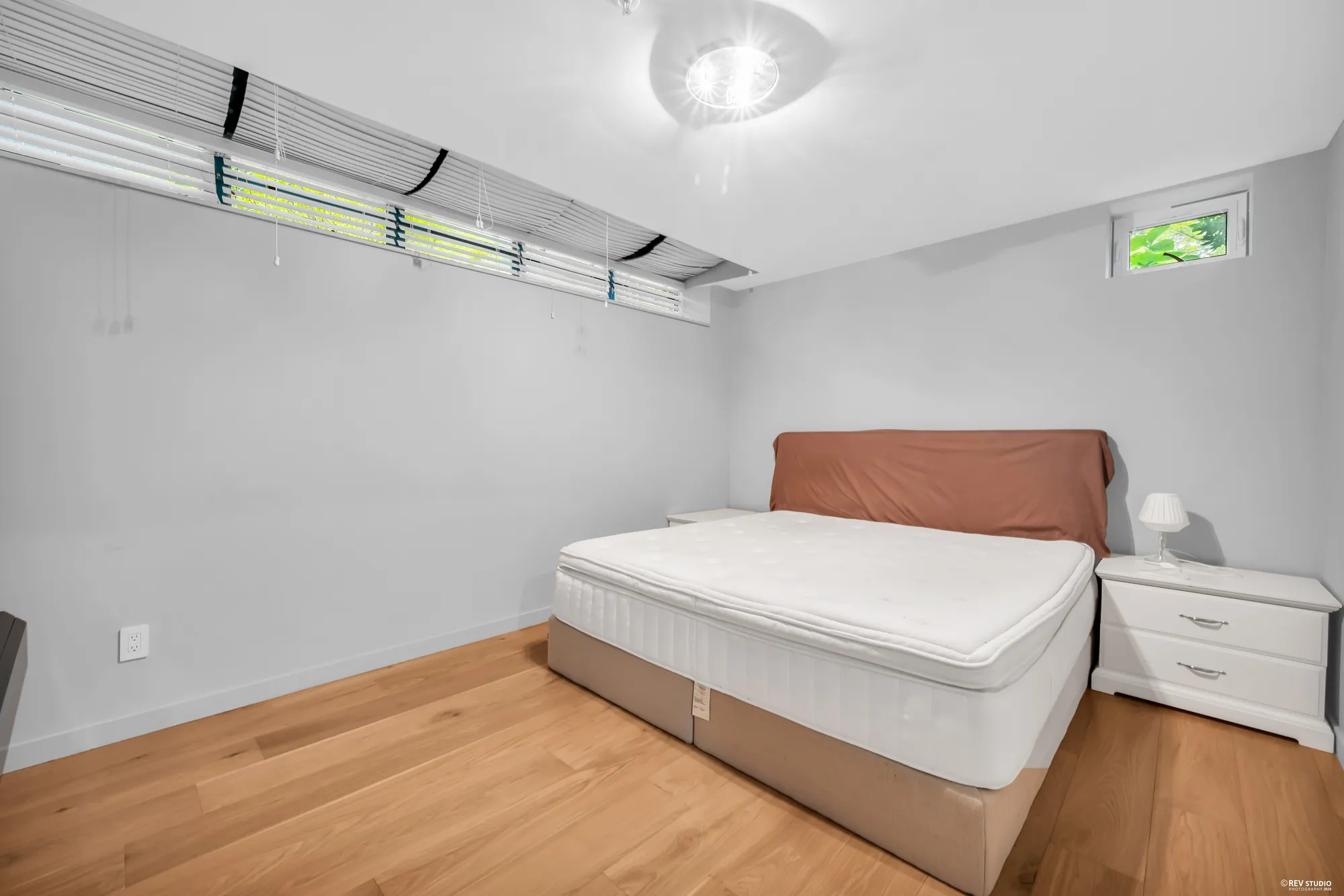 A lower bedroom with a bed frame and a long high window