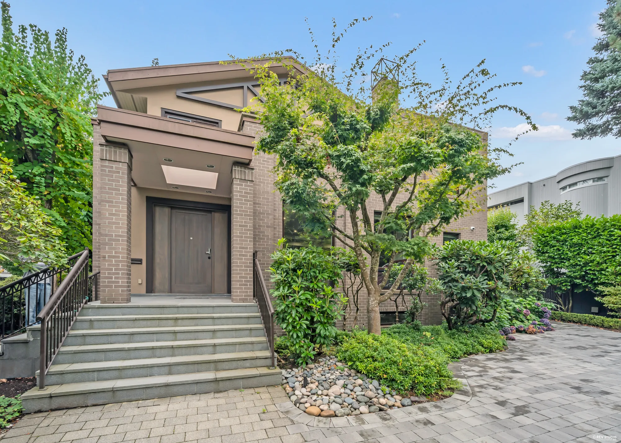 The front door up its steps between brick pillars, shrubs and a climbing vine either side
