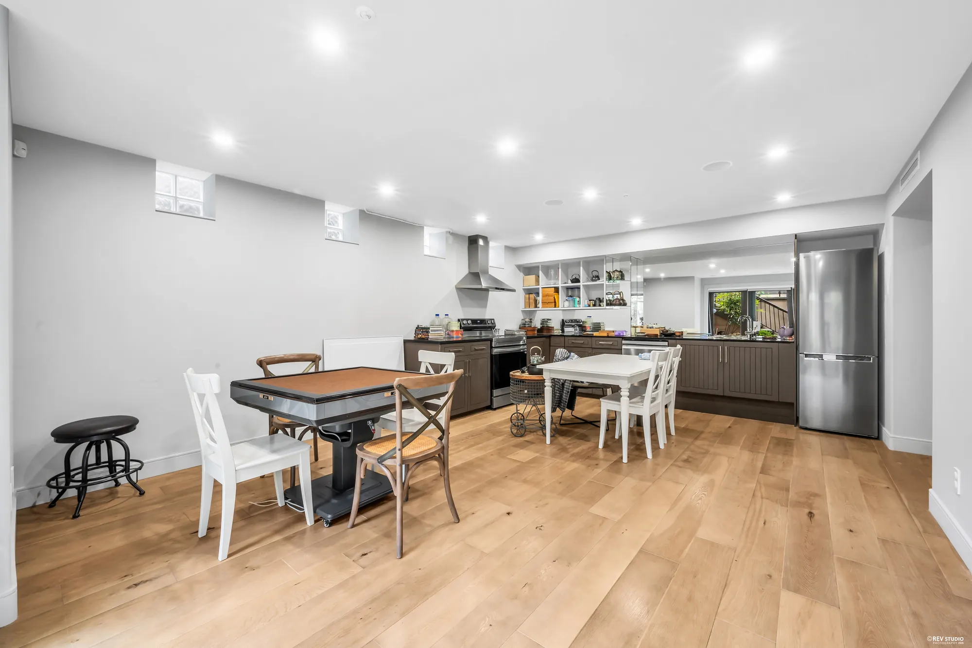 The lower kitchen and the recreation room in one open frame, the fridge and the range on the right