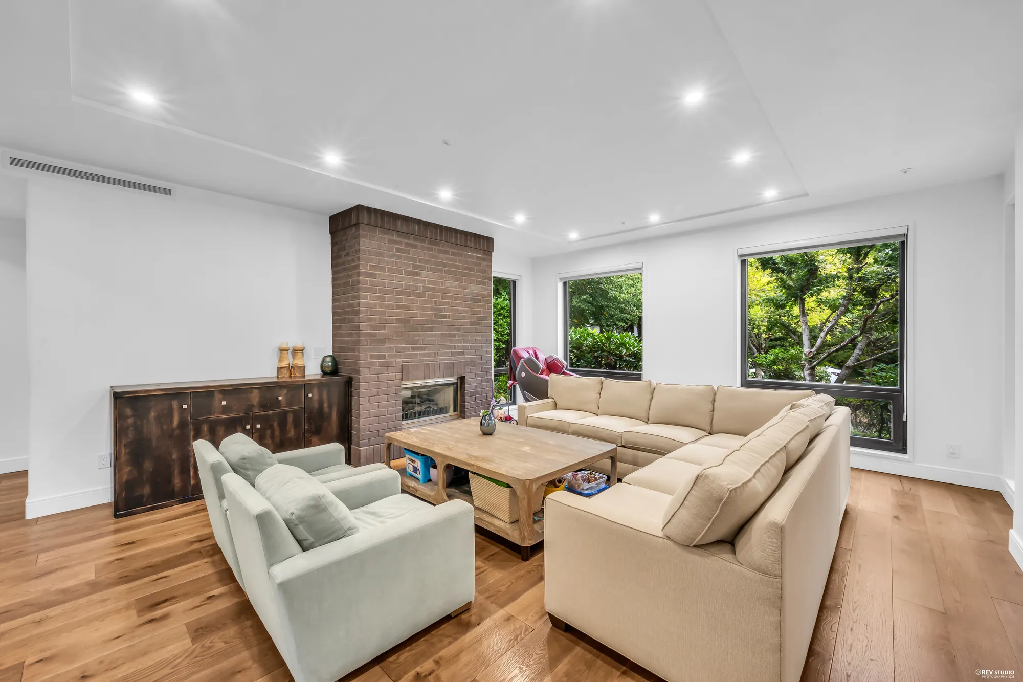The brick fireplace with a sideboard beside it and a window to the garden
