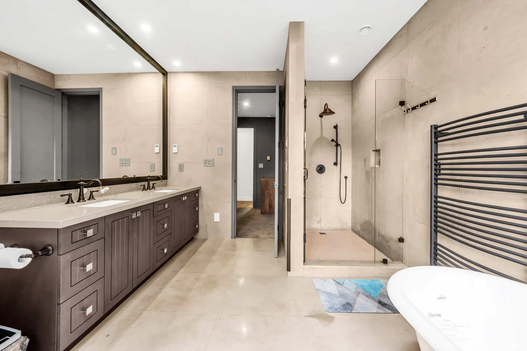 The primary bathroom: the glass shower and the vanity, the tub beyond