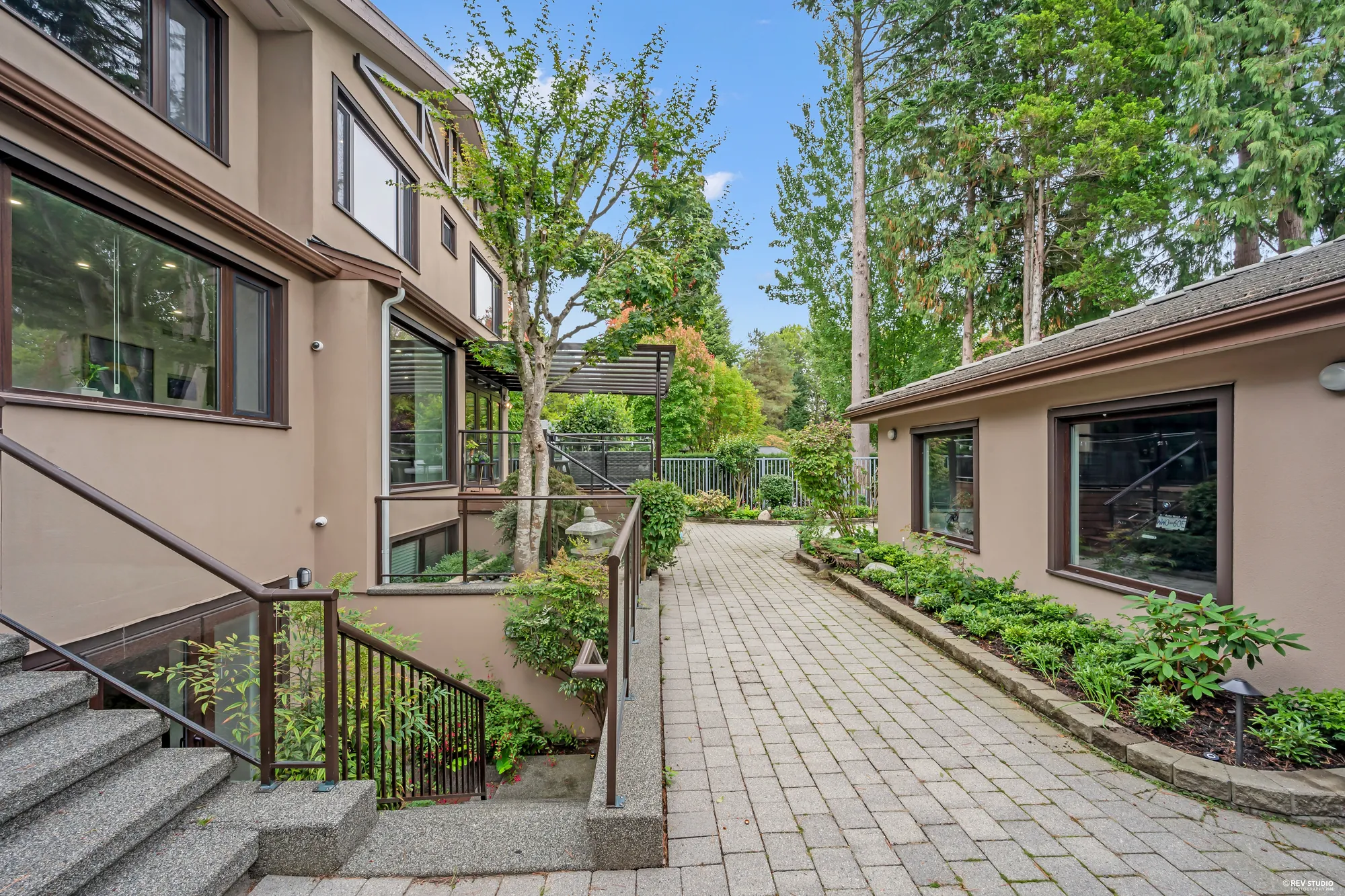 The paved side path between the house and the garage, the stair down to the lower patio on the left
