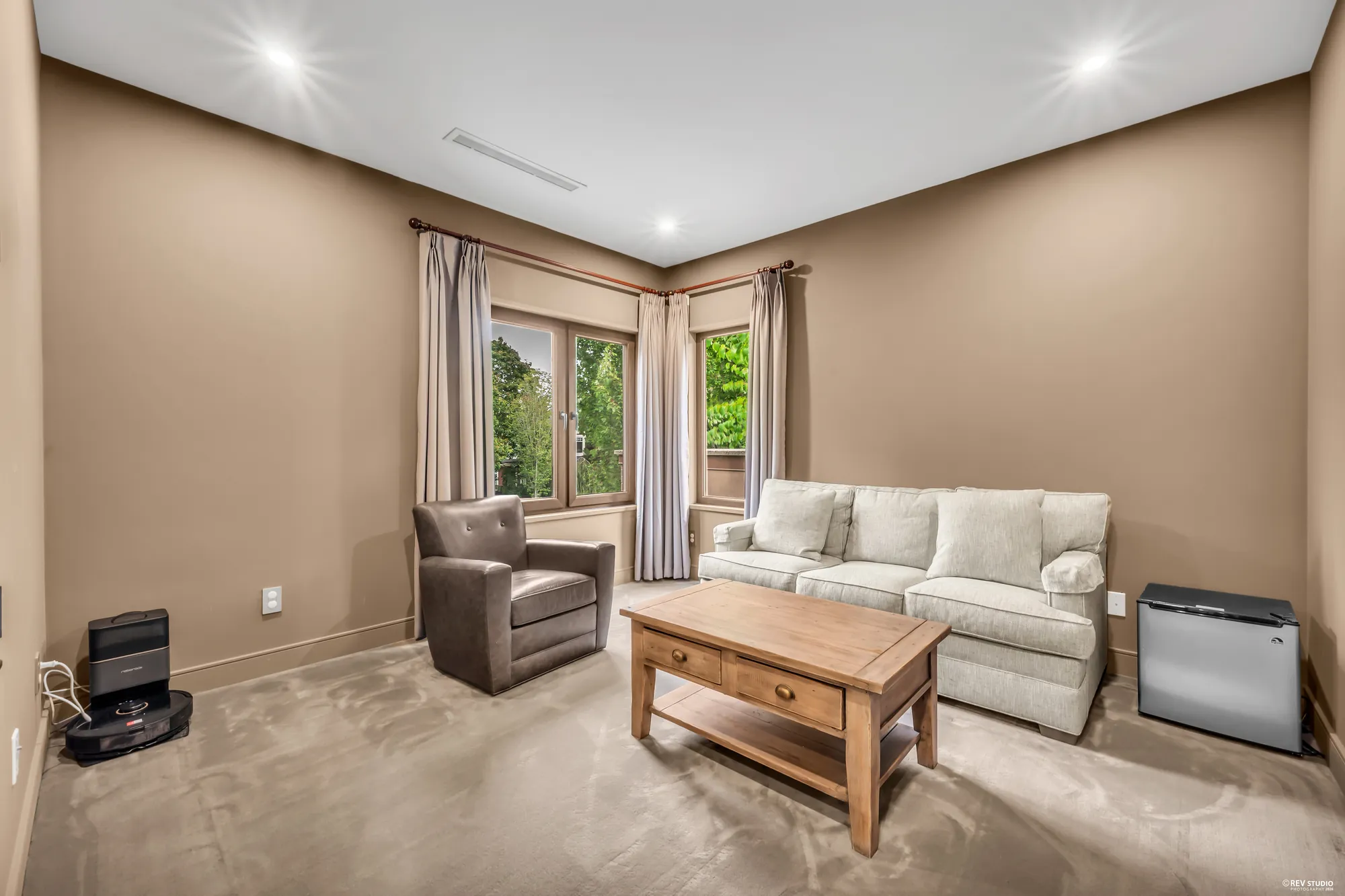 A room upstairs furnished as a sitting room: a sofa, an armchair and a coffee table, a window with curtains