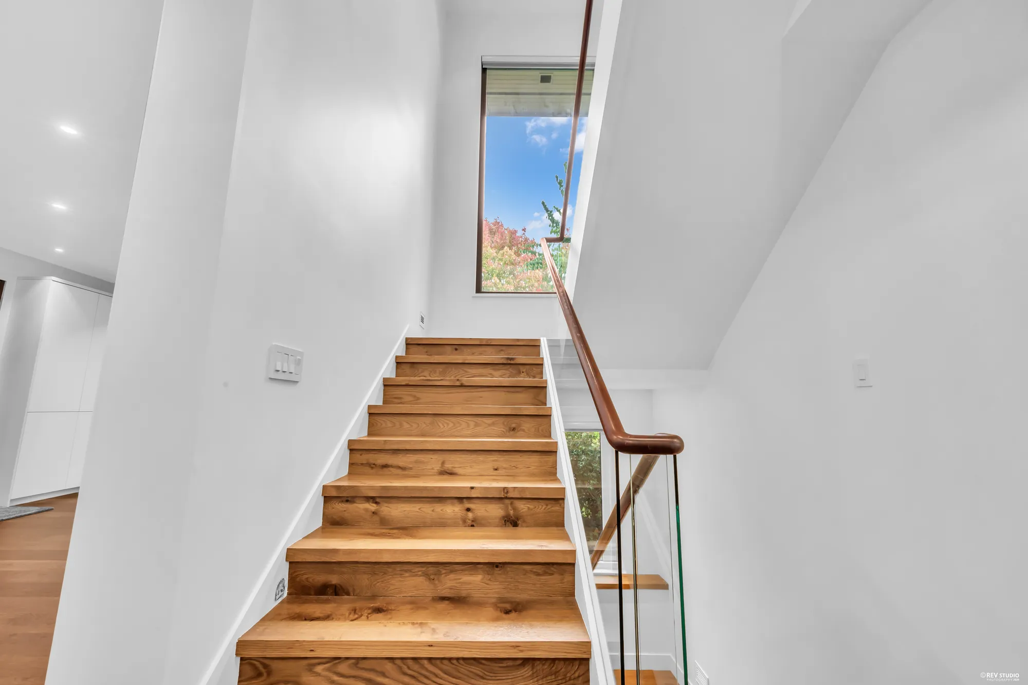 The oak stair rising past a tall window